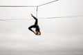 Brave blonde girl balancing on a slackline against the grey sky