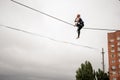 Brave blonde woman balancing on a slackline against the grey sky