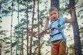 Brave boy walks sideways gently on swinging rope holding on rope above head