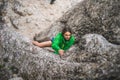 Brave Caucasian girl in a green coat climbing cliffs