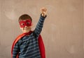 Brave cheerful boy in superhero cape and mask standing with hand on waist on beige background Royalty Free Stock Photo
