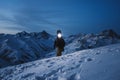 Brave explorer with headlamp commits a night climb to a steep snowy mountain. Wearing ski wear and backpack. Snowboar Royalty Free Stock Photo