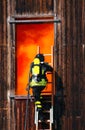 brave firefighter enters through a window with an oxygen tank during fire drills Royalty Free Stock Photo