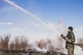 A brave firefighter puts out a grass fire in the villages close to the metropolis with the help of a water hydrant