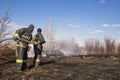 A brave firefighter puts out a grass fire in the villages close to the metropolis with the help of a water hydrant