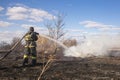 A brave firefighter puts out a grass fire in the villages close to the metropolis with the help of a water hydrant