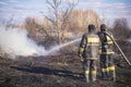 A brave firefighter puts out a grass fire in the villages close to the metropolis with the help of a water hydrant