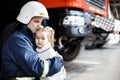 Brave firefighter in uniform holding little saved girl standing on black background