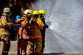 Brave firefighter using extinguisher and water from hose for fire fighting, Firefighter spraying high pressure water to fire,