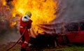 Brave firefighter using extinguisher and water from hose for fire fighting, Firefighter spraying high pressure water to fire,