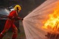 Brave firefighter using extinguisher and water from hose for fire fighting, Firefighter spraying high pressure water to fire,