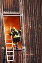 brave firefighters with oxygen cylinder goes into a house through a window during a fire