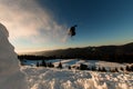 brave freerider jumping from the top of the snowy hill with skies. Splashing snow behind him