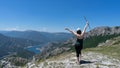 Brave girl conquering mountain peaks of mountains. Happy freedom hiker with hat and open arms Walking with wood stick, standing