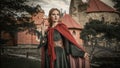 Brave heart young girl in the medieval green dress with a red cape