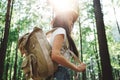 Brave hipster woman wearing backpack and hat traveling alone among trees in forest on outdoors