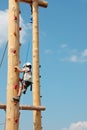 Brave little boy climbing up on a wooden pole for children climbing exercises