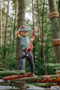 Brave little boy having fun at adventure park and smiling to camera wearing helmet. Scout practicing rappelling. Child - Royalty Free Stock Photo