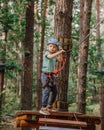 Brave little boy having fun at adventure park and smiling to camera wearing helmet. Scout practicing rappelling. Child - Royalty Free Stock Photo