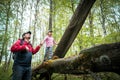 Brave little girl in spring forest is walking on log. Dad supports baby