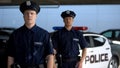 Brave male officers standing against squad car on background, important job