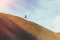 Brave man with backpack running and jumping on a dune