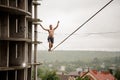 Brave man balancing on a slackline high against empty building and sky