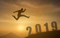 2019 brave man successful concept,silhouette man jumping over the sun between gap of the mountain to 2019 new year, feel like a wi