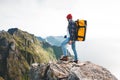 Brave man tourist with backpack standing on the edge mountain above sea and looking forward away