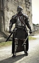 Brave medieval knight standing guard in a full suit of armor and holding a sword in defense of his castle.