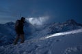 Brave night explorer climbs on high snowy mountains and lights the way with a headlamp. Extreme expedition. Ski tour. Snowboarder