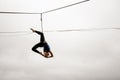 Brave slim blonde girl balancing on a slackline against the grey sky