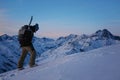 Brave snowboarder with backpack and snowboard climb at snowy mountain at evening