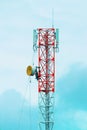 A brave telecommunications worker performs an extreme job, fixing a large cylindrical antenna component on a tall tower Royalty Free Stock Photo