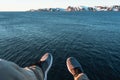 Brave traveler hipster sits on cliff in front of ocean and mountain