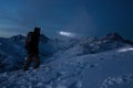 Brave traveler man commit ski tour on high mountain at night. Professional snowboarder lights the way with a headlamp. Backcountry