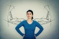 Brave woman, hands on hips, facing fears like a powerful hero as muscular arms sketches on the wall showing her inner strength. Royalty Free Stock Photo