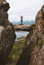 Brave woman traveler standing on hanging stone between rocks