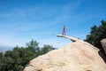 Brave young adult woman hiker stands on top of Potato Chip Rock in San Diego California