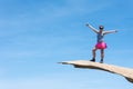 Brave young adult woman hiker stands on top of Potato Chip Rock in San Diego California