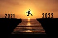Brave Young Man jumping over the cliff from 2021 to 2022 new year concept, silhouette Sunset background. Business Goal Achieve Royalty Free Stock Photo
