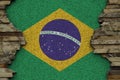 Brazil flag depicted in paint colors on old stone wall closeup. Textured banner on rock wall background