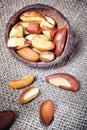 Brazil nuts in a coconut shell on linen background.