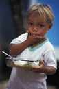 Brazilian blond child eating from saucepan.