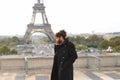 Mulatto laughing guy around Eiffel Tower with smartphone