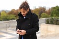 Mulatto laughing guy around Eiffel Tower with smartphone