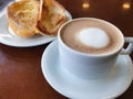 Brazilian breakfast. Capuccino cup and toasted bread with butter background