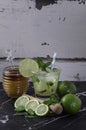 Brazilian caipirinha with honey, lemon slices and lemon kneader on a marble table