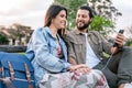 Couple listening music on mobile phone with headphones in bench park Royalty Free Stock Photo