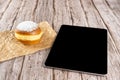 Brazilian cream doughnuts on a brown paper next to a tablet